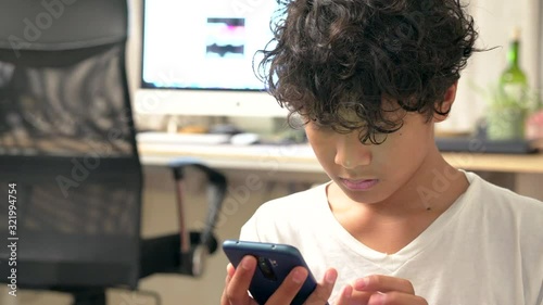 Boy playing on a smartphone in the house