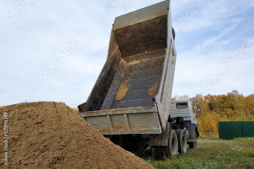 Photography A dump truck unloads sand at a construction site to mix cement.