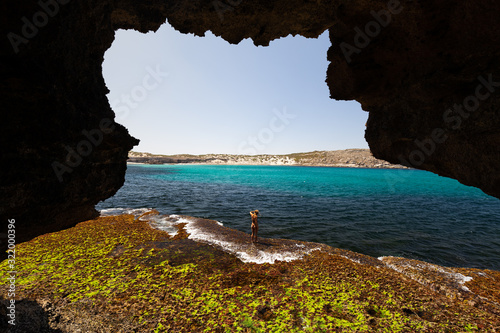 View from cave of woman in bikini exploring rugged limestone coastline on sunny day on the Great Australian Bight in South Australia