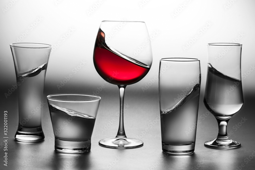 Some glasses of water in black and white and a glass of red wine Some glasses of water in black and white and a glass of red wine