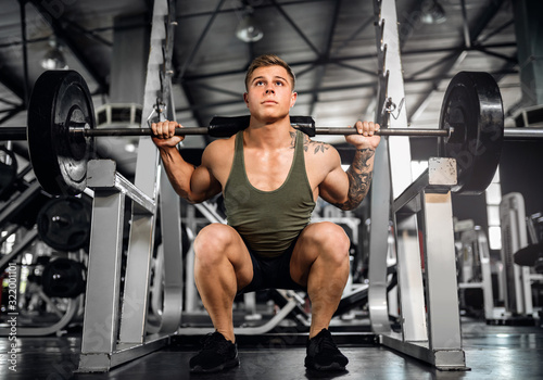 Young attractive muscular gen z body builder doing back squats