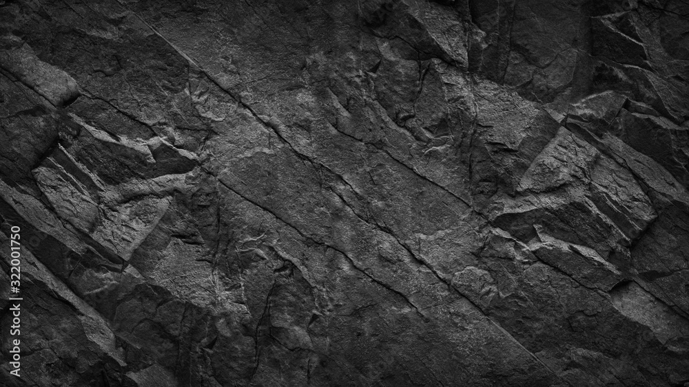 Black grunge background. Dark gray rock texture. Cracked rough stone surface. Mountain texture closeup. Black and white background. Volume. 3D effect.