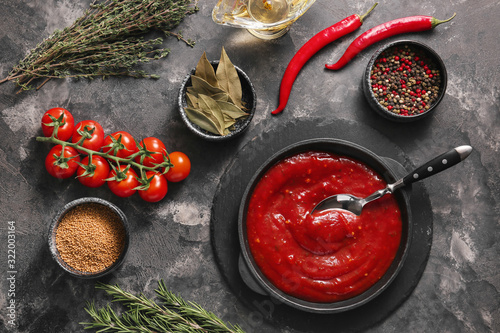 Pan with tomato sauce and ingredients on dark background