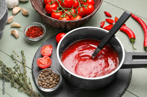 Saucepan with tomato sauce on table