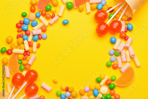 Frame made of tasty candies on color background