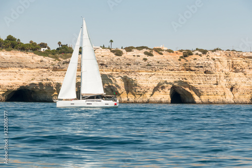 sailboat off the cliffs and caves in the Algarve, southern Portugal