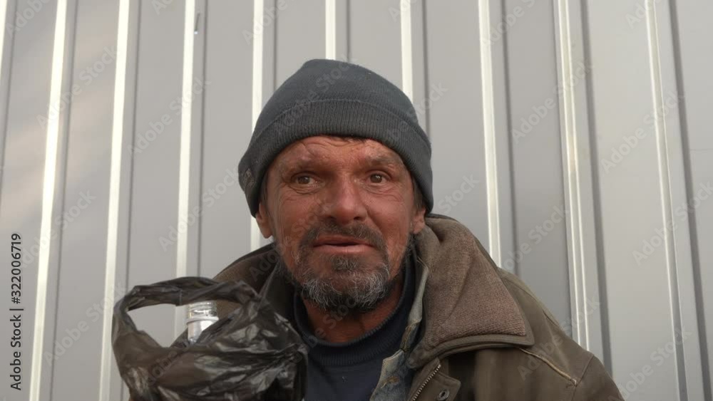 Homeless man holding bottle of alcohol in a bag. Homelessness alcoholism problem