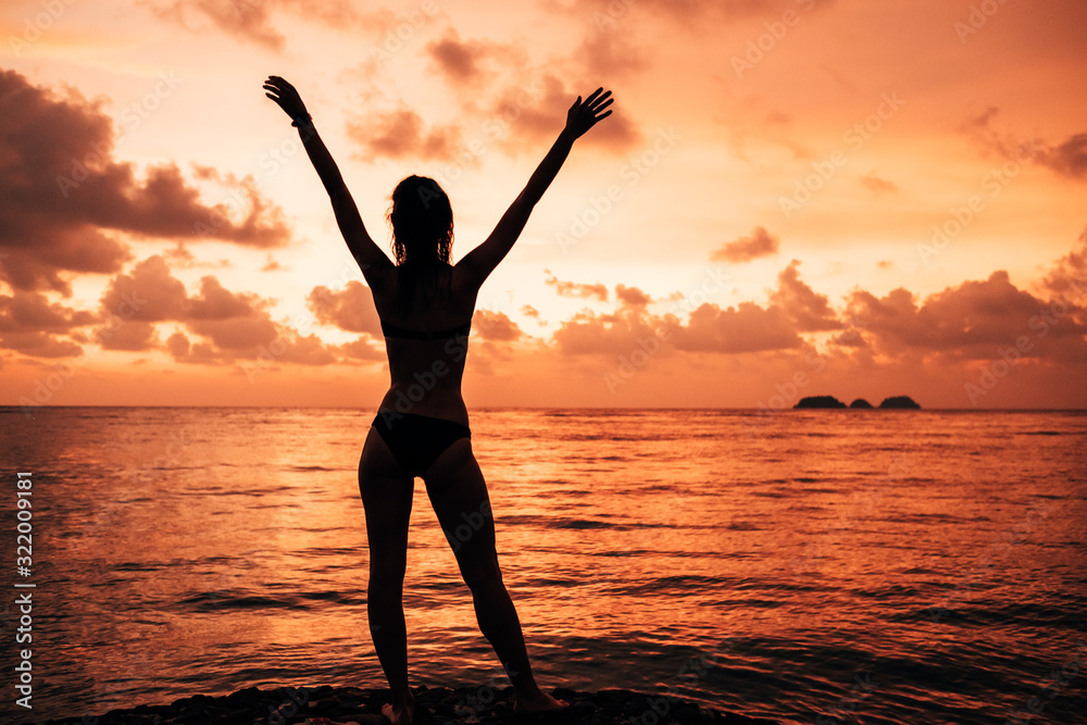 Lady's silhouette with raised arms against sunset