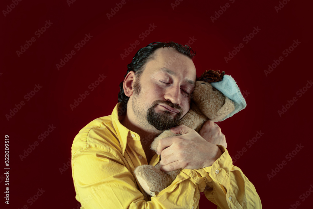 A funny ugly man hugging a cute teddy bear (a plush toy). Concept: affection, emotions, childhood memories. A funny ugly man hugging a cute teddy bear (a plush toy). Concept: affection, emotions, childhood memories.