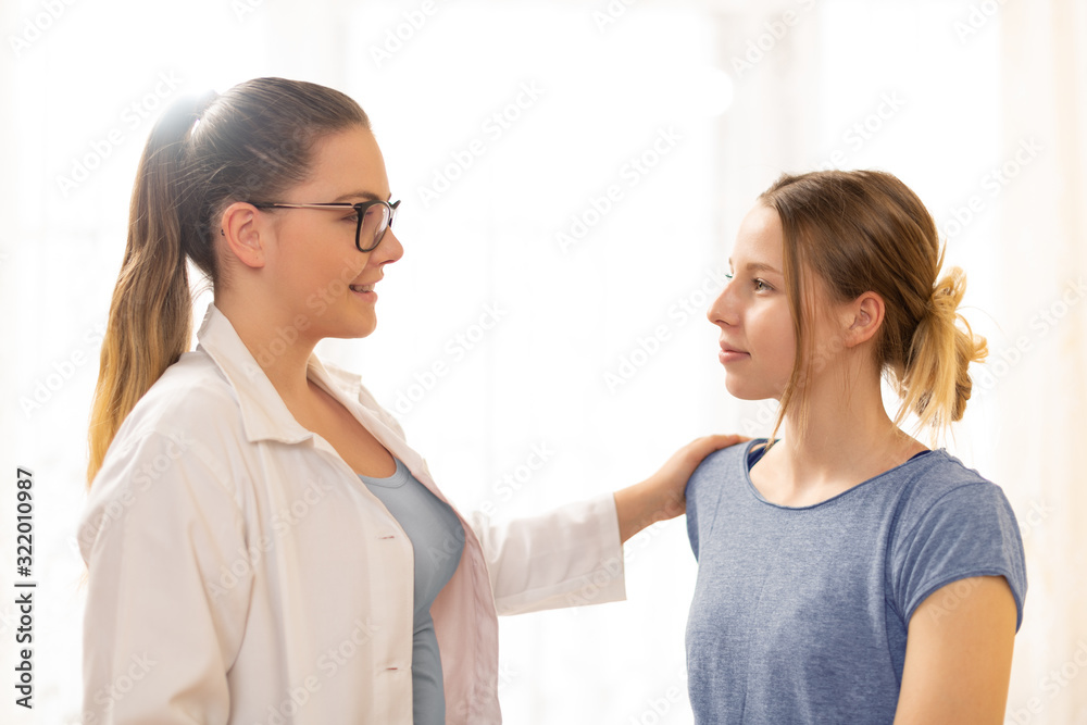 Caring physiotherapist or a doctor consulting with her young female patient at her office. Caring physiotherapist or a doctor consulting with her young female patient at her office.