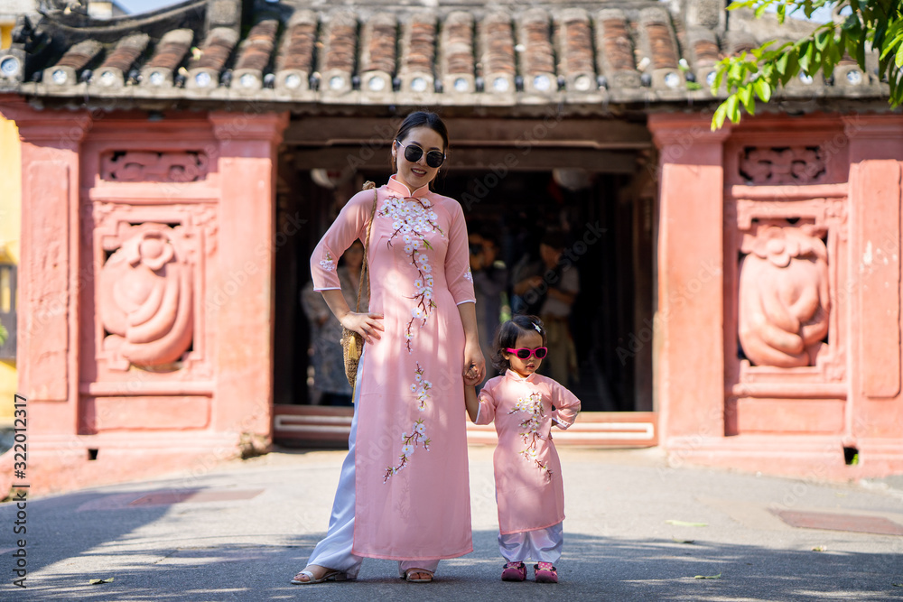 Young mum walking on street at Hoi An Ancient town with her daughter. Young mum walking on street at Hoi An Ancient town with her daughter.