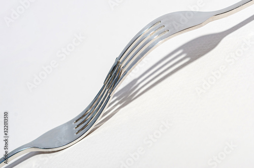 Two metal shiny forks on a light background.