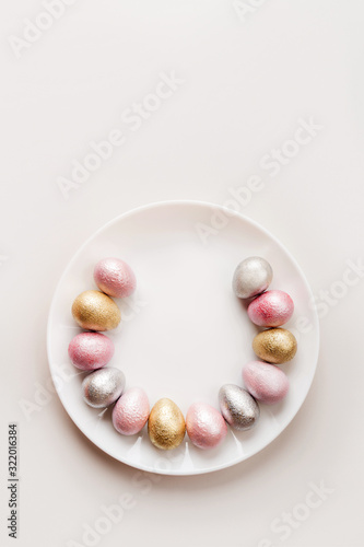 Colored painted pearl chicken and quail eggs of pink, silver golden color on a purple plate pastel background. Minimalistic creative idea easter festive vertical wallpaper flat lay. Copyspace for text