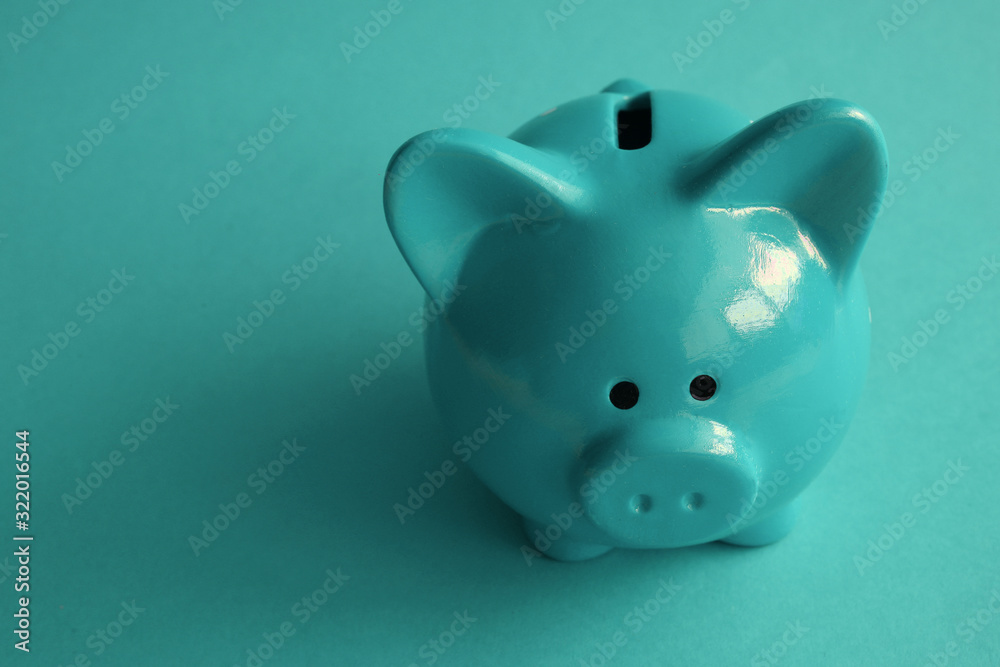 Stylish modern piggy bank on a turquoise background closeup Stylish modern piggy bank on a turquoise background closeup