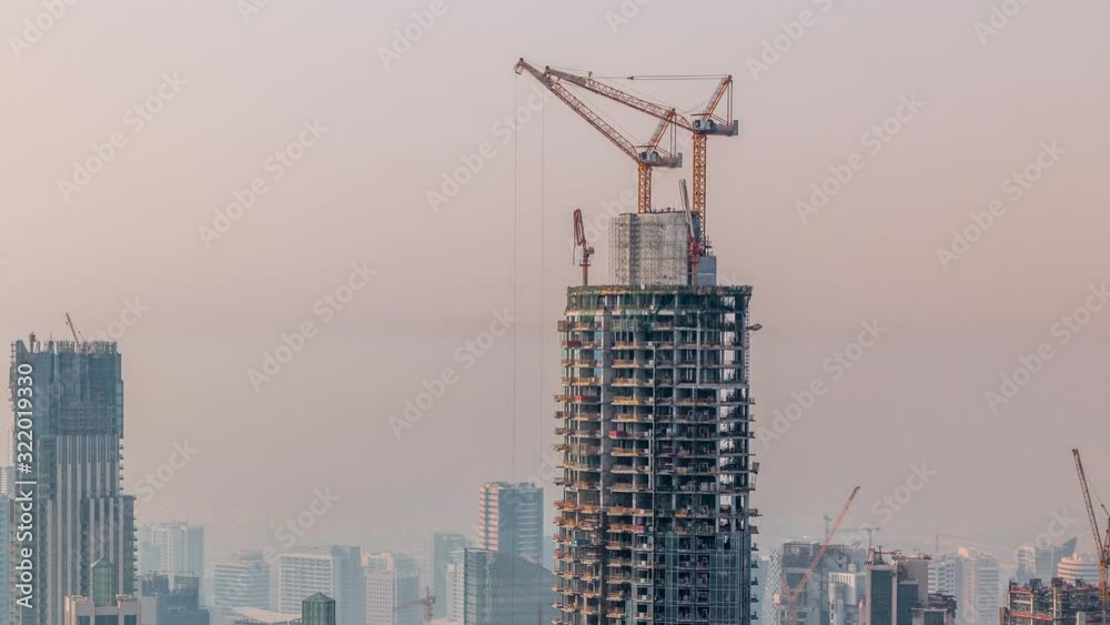 Construction progress of new modern skyscraper in Dubai city aerial timelapse, United Arab Emirates. Cranes and building equipment in downtown Construction progress of new modern skyscraper in Dubai city aerial timelapse, United Arab Emirates. Cranes and building equipment in downtown