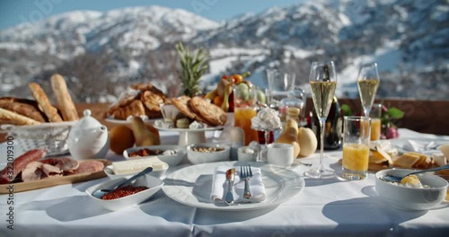 Close up shot of a luxurious breakfast with various fruits, snacks and champagne served on terrace with beautiful view on winter mountains - luxury lifestyle concept 4k footage photo