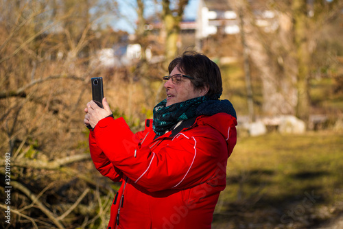 A woman smiles as she makes a photo with her smartphone