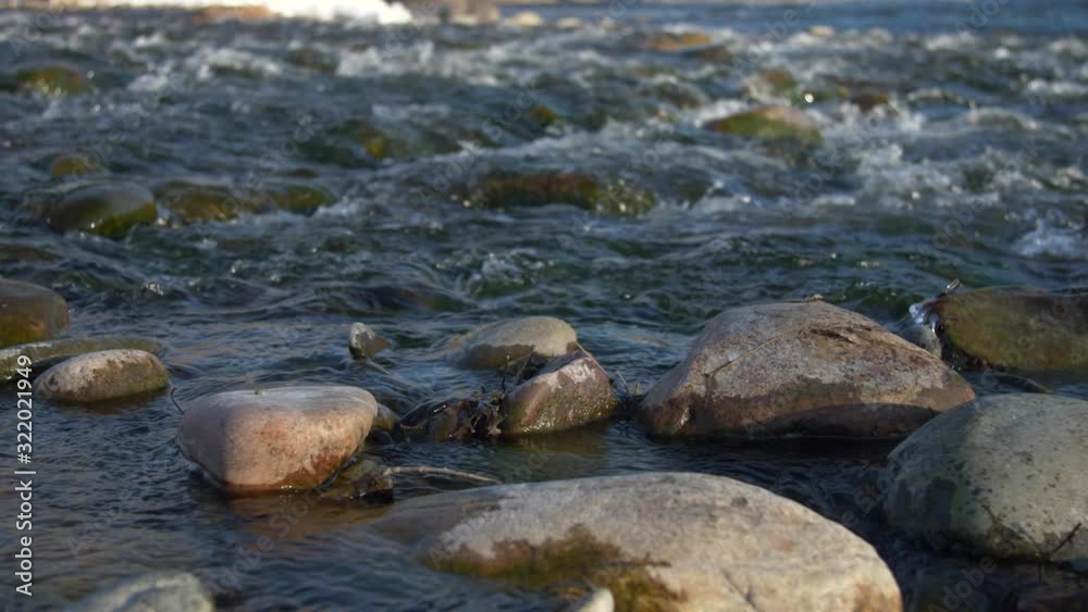 Slow motion low angle slider moving over river rocks looking at small rapids. Shallow focus in background. Sunset/Golden Hour. Slow motion low angle slider moving over river rocks looking at small rapids. Shallow focus in background. Sunset/Golden Hour.