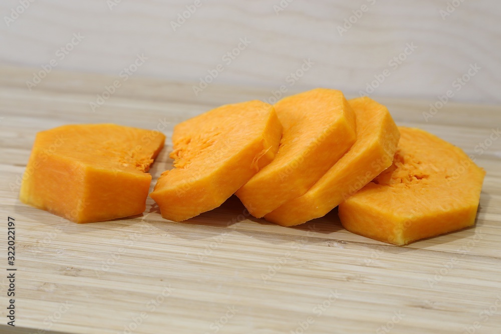 The interior of a soft orange-coloured pumpkin is cut with pieces on a board before making porridge or soup The interior of a soft orange-coloured pumpkin is cut with pieces on a board before making porridge or soup