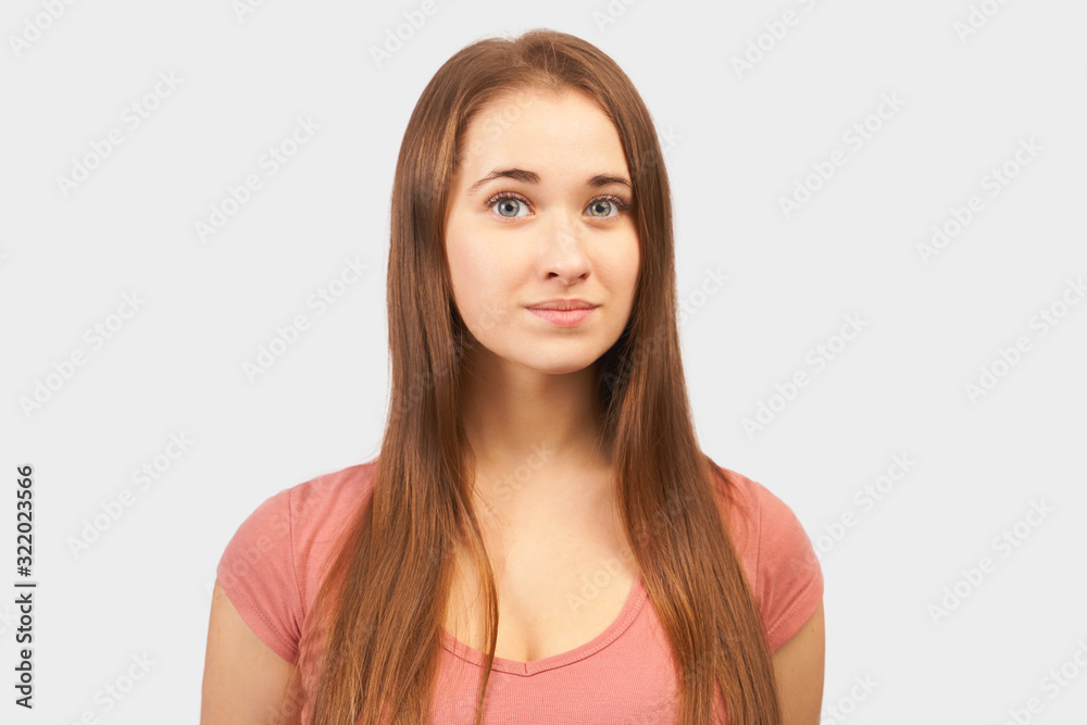 Sweet looking girl looks at camera, gentle soft smile, self confidence. Beautiful young woman with long hair, clean smooth skin wears pink t-shirt isolated on background in Studio Sweet looking girl looks at camera, gentle soft smile, self confidence. Beautiful young woman with long hair, clean smooth skin wears pink t-shirt isolated on background in Studio