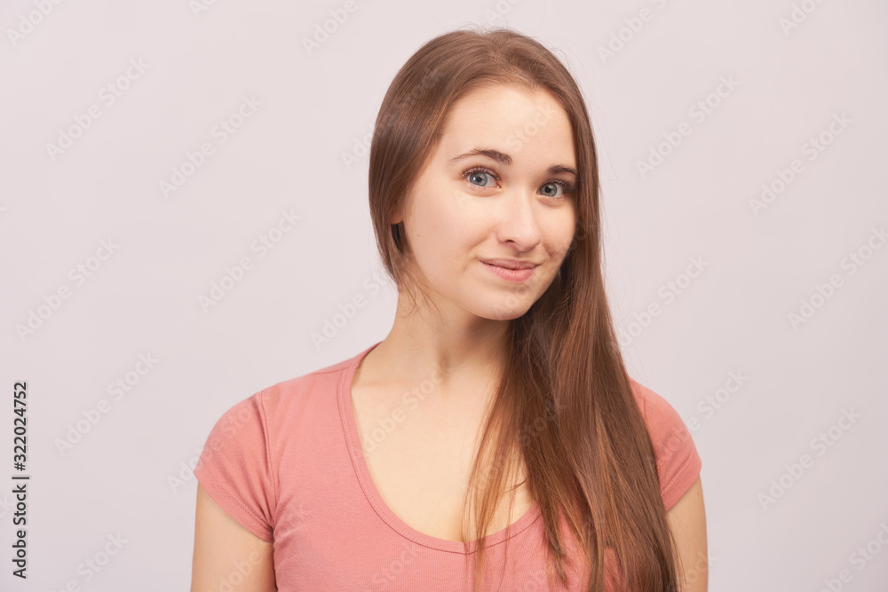 Portrait of smiling girl grins at camera, grinning, eyes glistening. Beautiful young woman with long hair isolated on white background in Studio with an empty space for text and advertising. Portrait of smiling girl grins at camera, grinning, eyes glistening. Beautiful young woman with long hair isolated on white background in Studio with an empty space for text and advertising.
