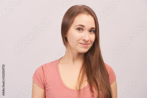 Portrait of smiling girl grins at camera, grinning, eyes glistening. Beautiful young woman with long hair isolated on white background in Studio with an empty space for text and advertising.
