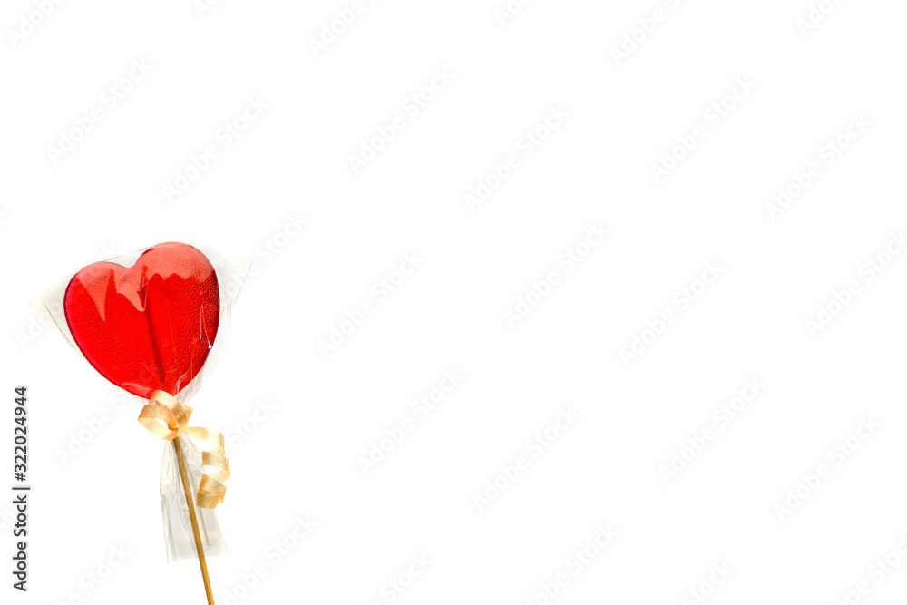 Lollipop. One red heart-shaped Lollipop in transparent packaging  left on a white isolated background, right space for text for Valentine's Day. Isolate.