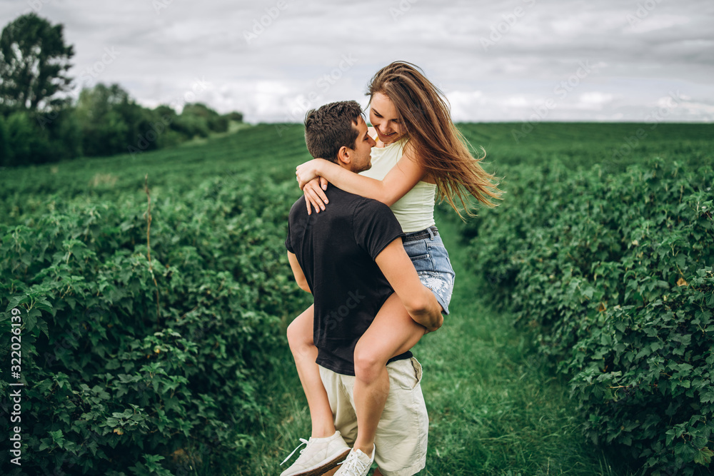A tender loving couple walking in a field of currant. Man whirls woman in her arms. Love story A tender loving couple walking in a field of currant. Man whirls woman in her arms. Love story