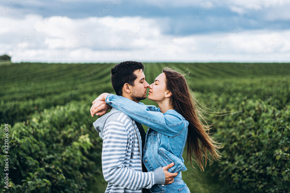 Young loving couple gently hugging on the background of green currant plantations. Love Story Young loving couple gently hugging on the background of green currant plantations. Love Story