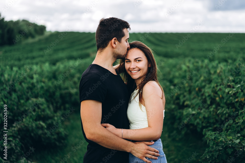 Young loving couple gently hugging on the background of green currant plantations. Love Story