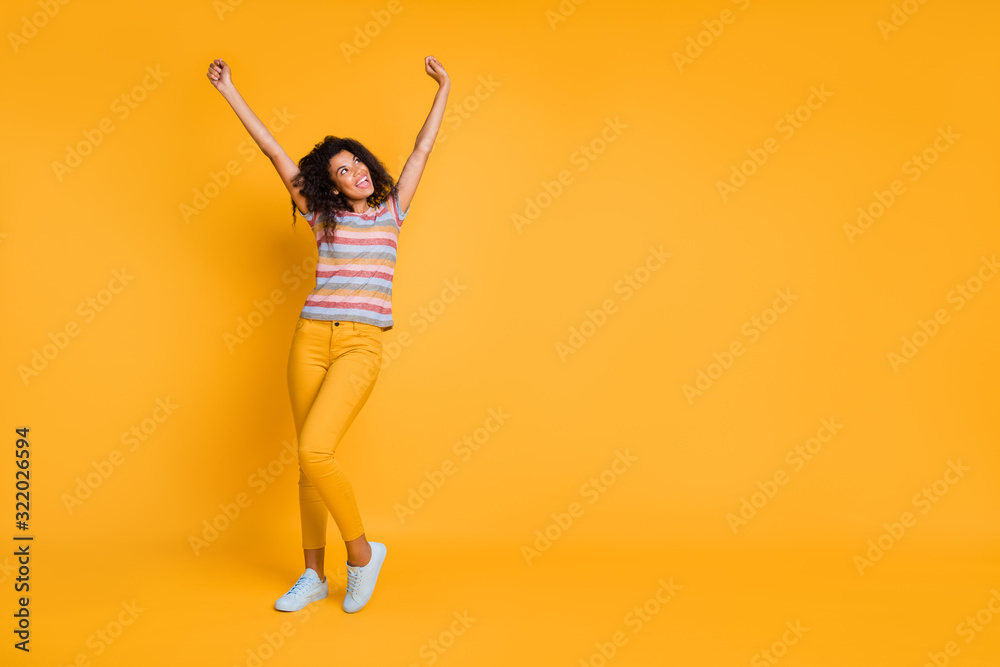 Full length body size view of nice attractive glad cheerful cheery wavy-haired girl wearing striped t-shirt rising hands up having fun isolated on bright vivid shine vibrant yellow color background Full length body size view of nice attractive glad cheerful cheery wavy-haired girl wearing striped t-shirt rising hands up having fun isolated on bright vivid shine vibrant yellow color background
