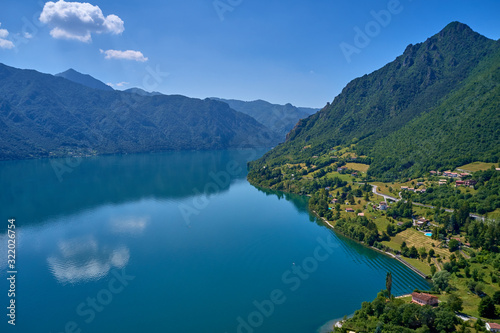 Panoramic view of the mountains and Lake Idro.  Reflection in the water of the mountains  trees  blue sky. Aerial view  drone photo