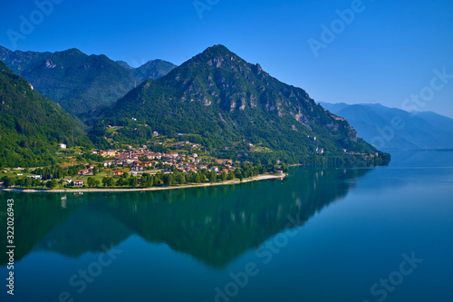 Panoramic view of the mountains and Lake Idro. Reflection in the water of the mountains, trees, blue sky. Aerial view, drone photo