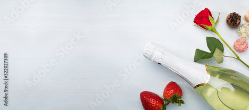 Red rose, strawberries, chocolates and champagne on a white background with a copyspace.