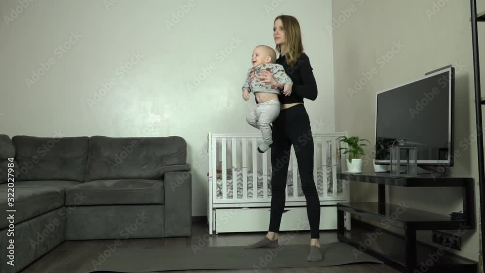 Young mother performs an exercise at home with her child. Young mother performs an exercise at home with her child.