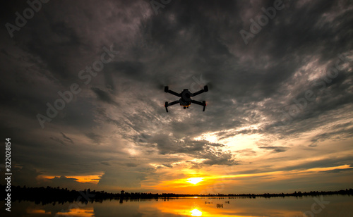 drone quadcopter with digital camera flying at sunset.Dark Flying drone and cloud sunrise sky.