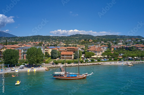 Aerial photography. Beautiful coastline. In the city of Bardolino, Lake Garda is the north of Italy. View by Drone. Large sailboat parked in port.