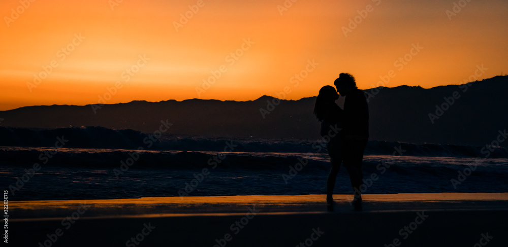 silhouette of couples in love on the beach at sunset