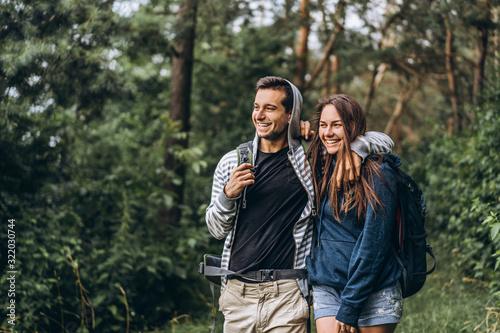 Young couple with backpacks on their backs smiling and walking in the forest, enjoy the walk