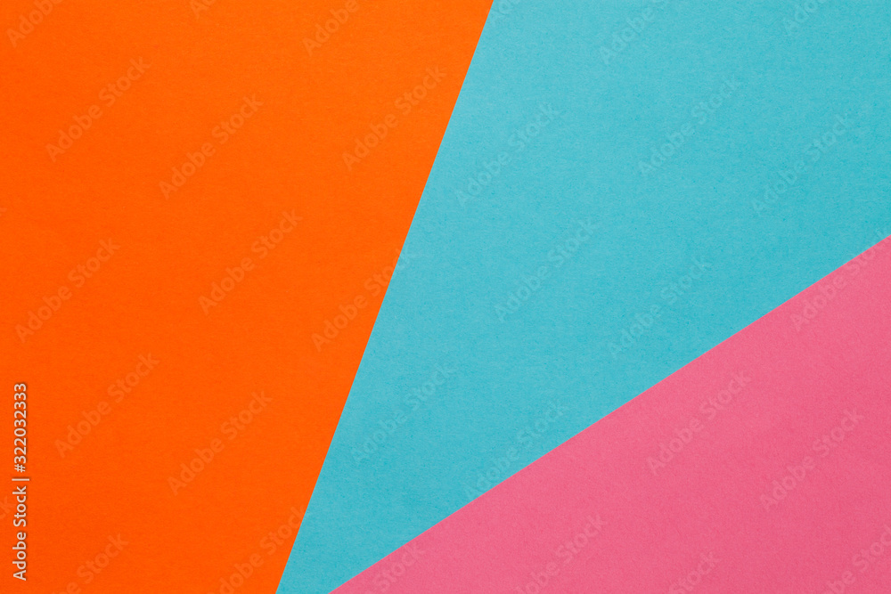 Background of three sheets of colored paper, orange, blue, pink.