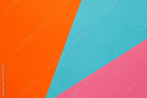 Background of three sheets of colored paper, orange, blue, pink.