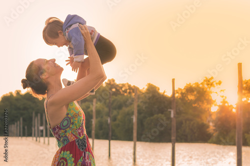  madre alsa  a su  hijo atardecer en el rio con felicidad photo