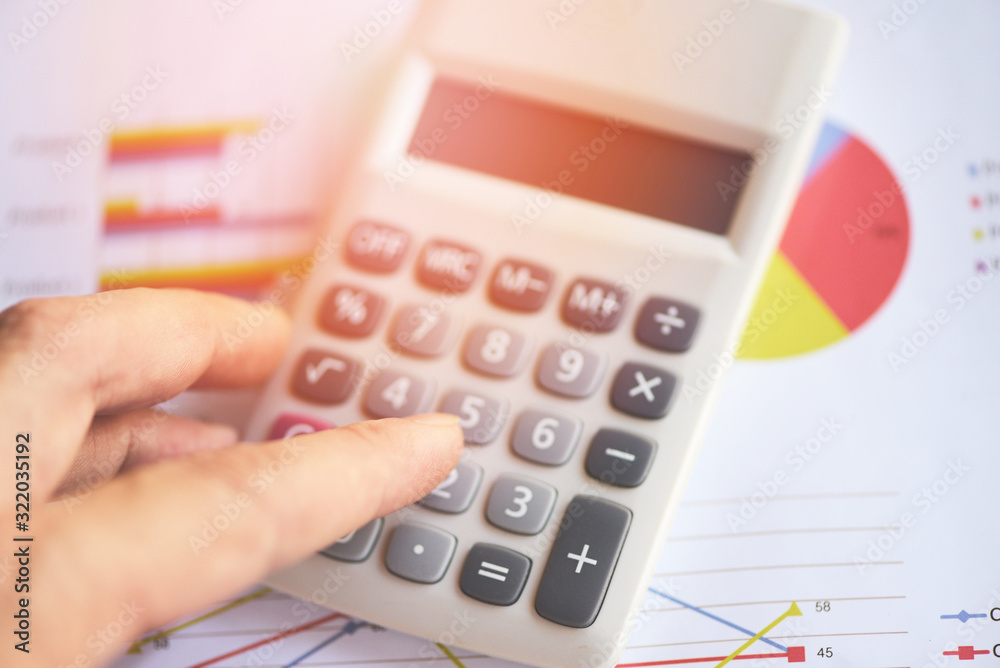 Business man using calculator for report financial statistics documents on infographics at office table close up - Sales report concept Business man using calculator for report financial statistics documents on infographics at office table close up - Sales report concept
