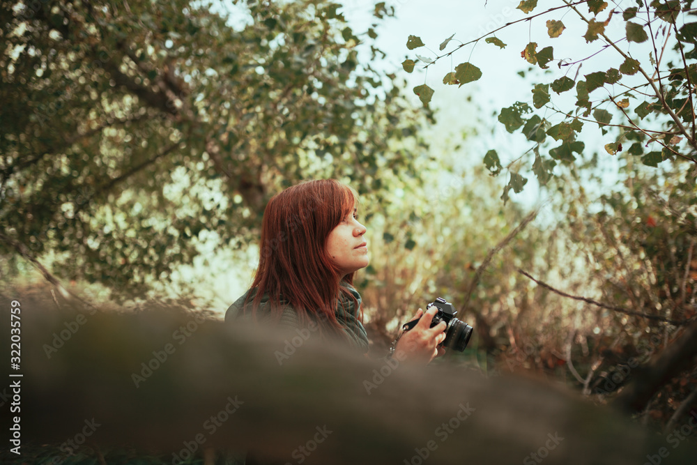 Young woman taking photos in the forest with an old camera Young woman taking photos in the forest with an old camera