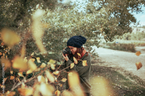 Young woman taking photos in the forest with an old camera