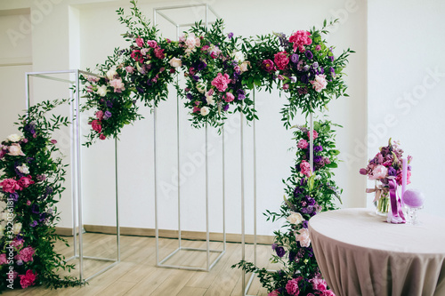Beautiful wedding arch in the restaurant decorated with fresh pink and purple flowers