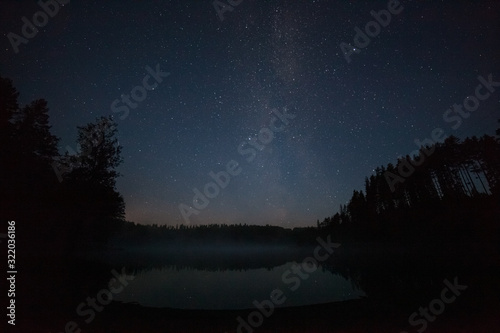one million stars over the lake at night. long exposure. Trail from a flying satellite. Milky way