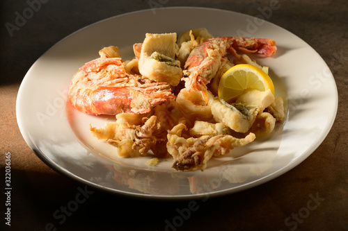Grilled Calamari (Squid) and shrimps with lemon and parsley on white plate on a plate in restaurant ready to be served
