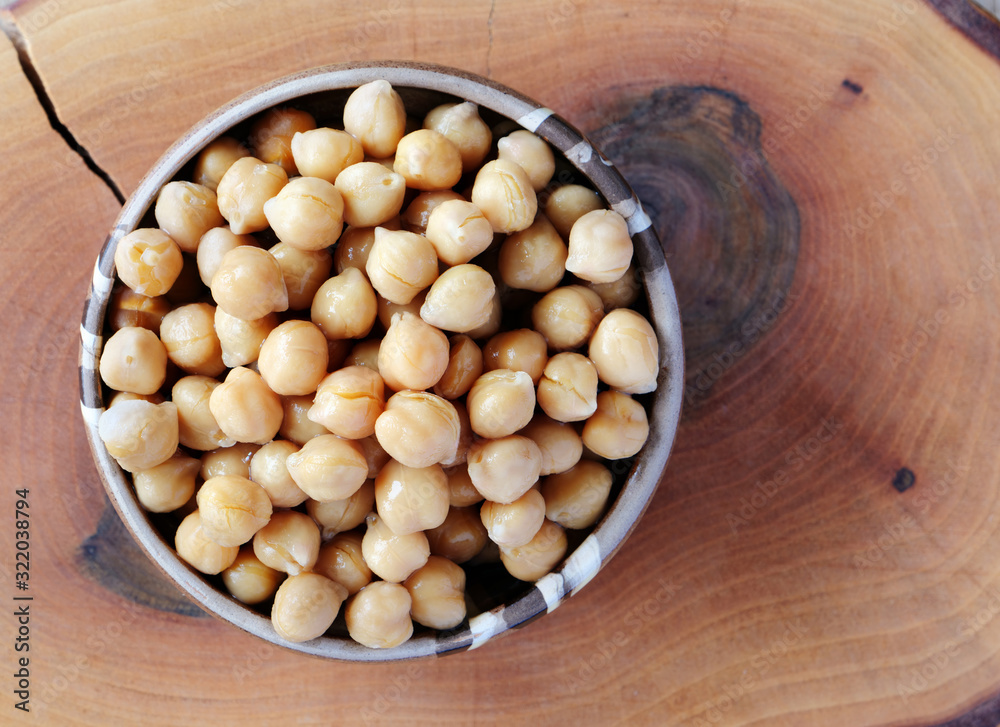 Tinned chickpeas in ceramic bowl over wooden board, flat lay Tinned chickpeas in ceramic bowl over wooden board, flat lay