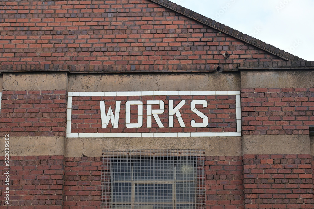 Φωτογραφία Works Sign in Glazed White Brick on Wall of Old Factory Building